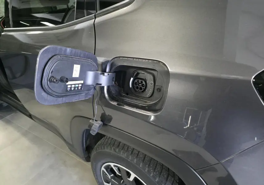 Prise de recharge ouverte côté gauche arrière d’un Jeep Compass gris métallisé avec jante noire et argent.