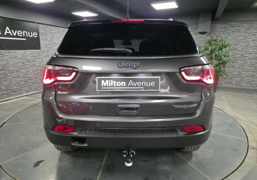 Vue arrière d'un Jeep Compass gris métallisé avec hayon électrique et attelage fixe visible en intérieur.