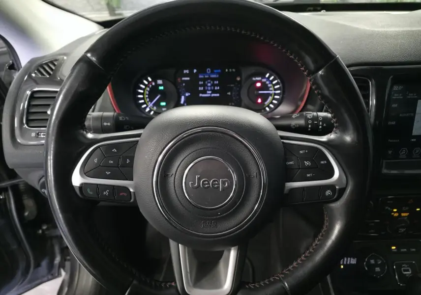 Vue rapprochée du volant noir en cuir avec commandes multifonctions du Jeep Compass Trailhawk hybride rechargeable.