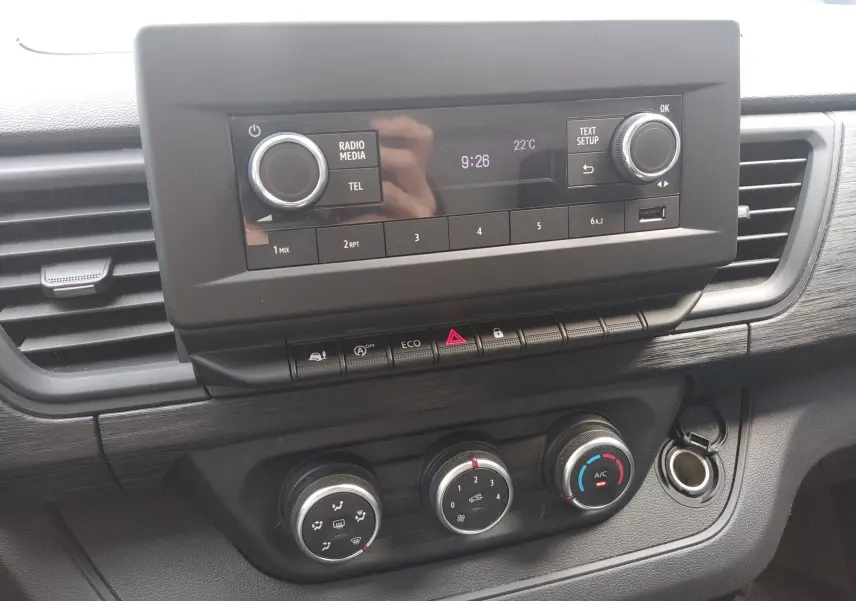 Vue rapprochée de la console centrale du Renault Trafic Fourgon blanc 2024, avec commandes climatisation et radio.