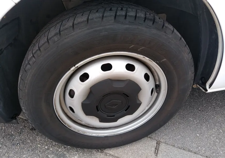 Gros plan sur la roue avant droite du Renault Trafic blanc, mettant en valeur la jante acier avec enjoliveur noir.