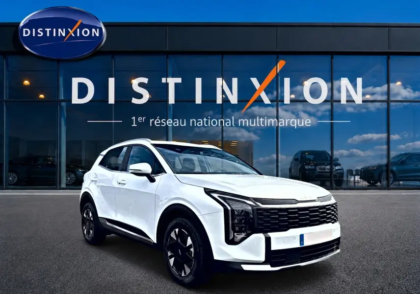 KIA SPORTAGE 1.6 hybride blanc vu en 3/4 avant droit devant une vitrine avec logo Distinxion.