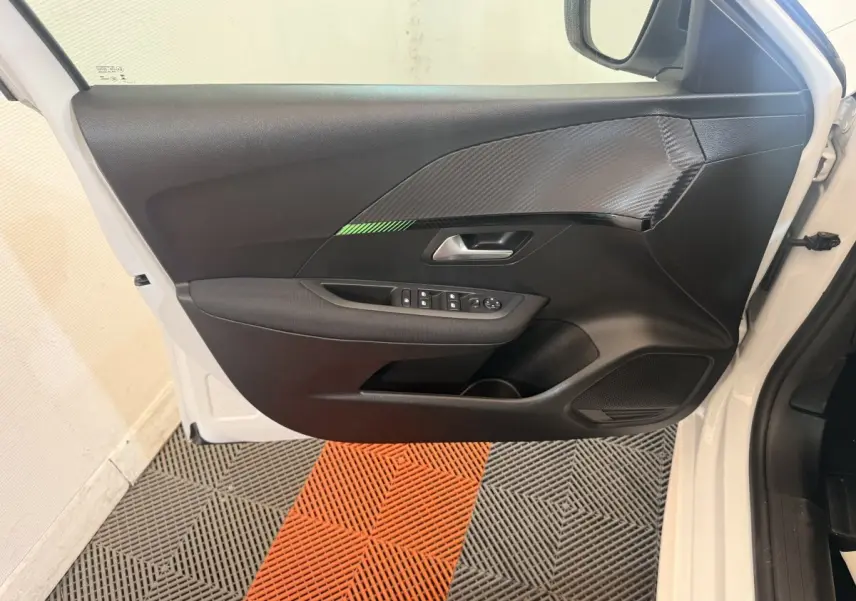 Vue intérieure de la porte avant gauche blanche de la Peugeot 208 2025 avec insert noir texturé et commandes électriques.