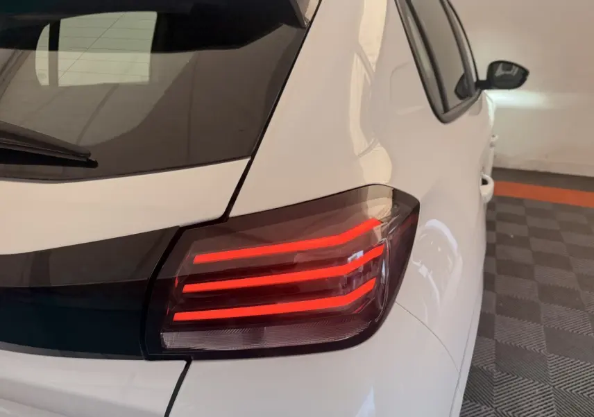 Feu arrière droit allumé d'une Peugeot 208 blanche vue en léger angle arrière dans un garage.