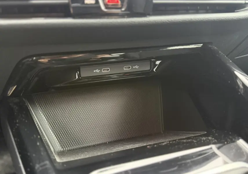 Gros plan sur la console centrale noire du Volkswagen Golf VIII avec deux ports USB-C intégrés.