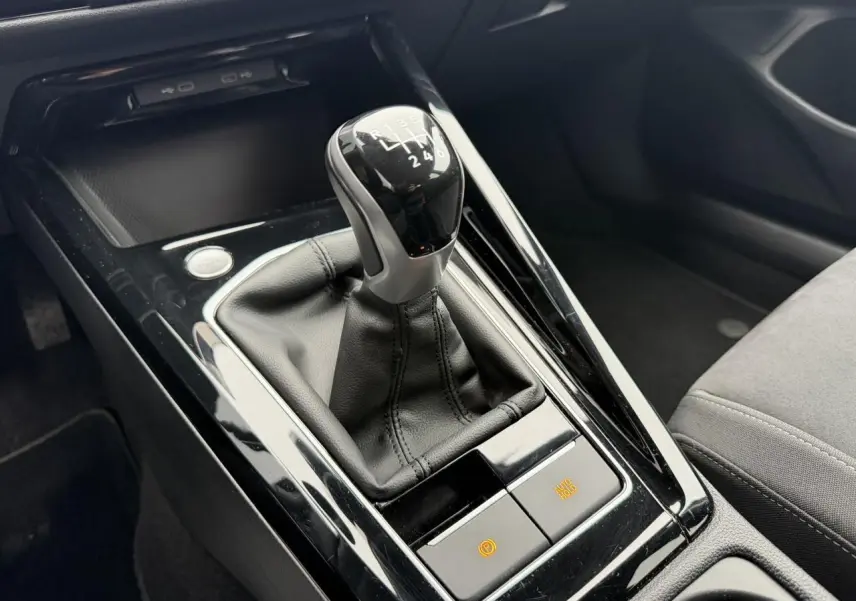 Gros plan sur la commande de boîte manuelle noire avec soufflet cuir dans l'habitacle gris de la Volkswagen Golf VIII.