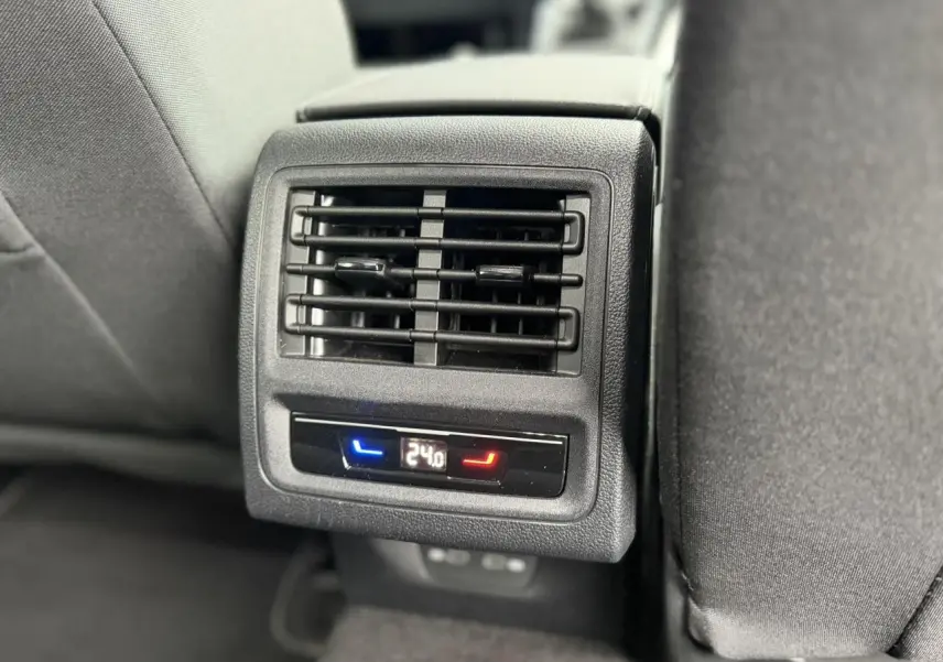 Gros plan sur la sortie d’air arrière avec réglage de température à 24°C dans l’habitacle noir d’une Volkswagen Golf VIII.