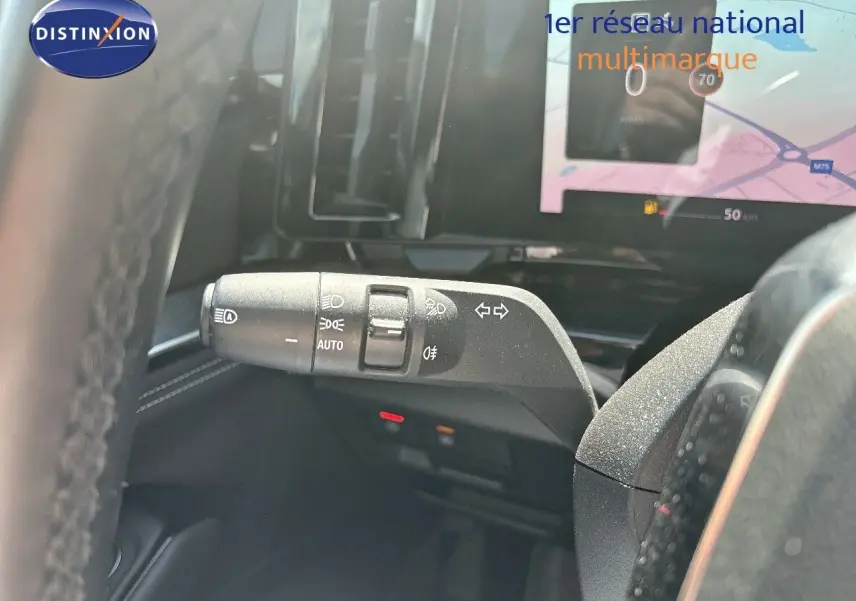 Gros plan sur la manette de clignotants et feux du Renault Austral gris schiste, avec écran tactile en arrière-plan.