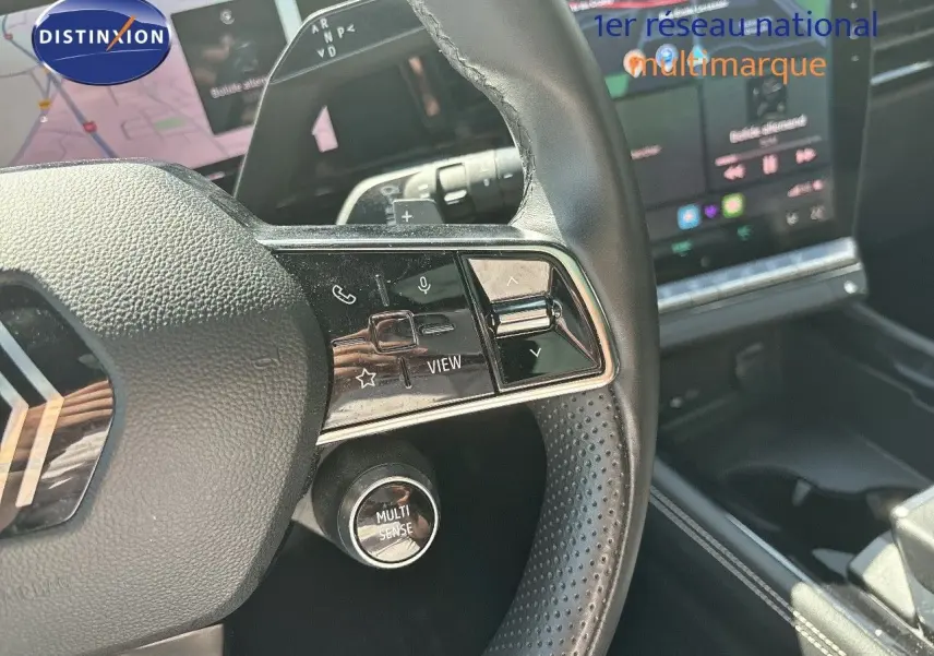 Gros plan sur le volant noir perforé du Renault Austral 2024 avec commandes intégrées et bouton Multi-Sense visible.