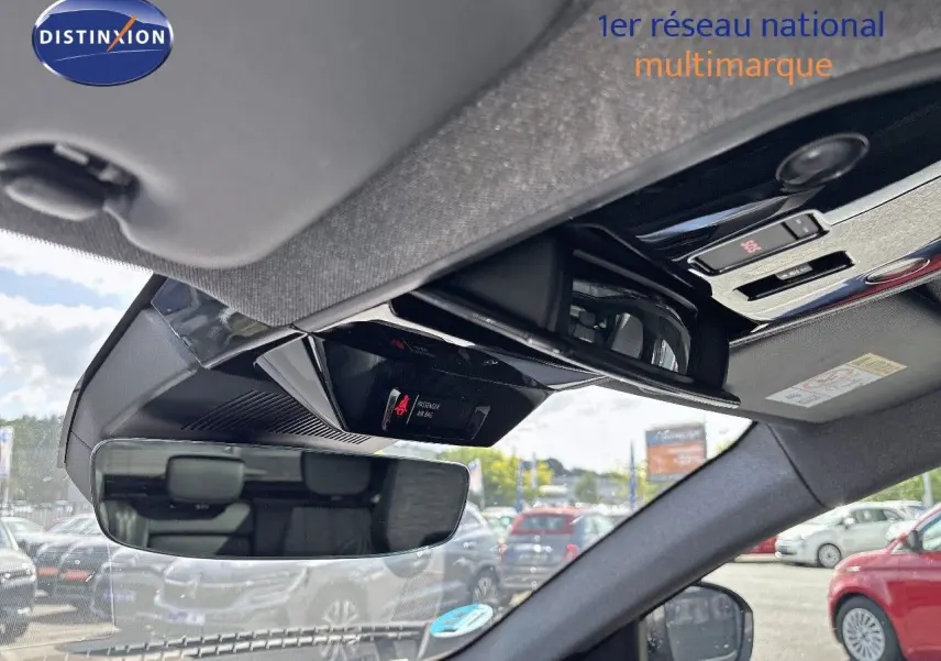 Vue intérieure du rétroviseur central et du plafond de toit du Renault Austral gris schiste, avec commandes et ciel visible à l'extérieur.