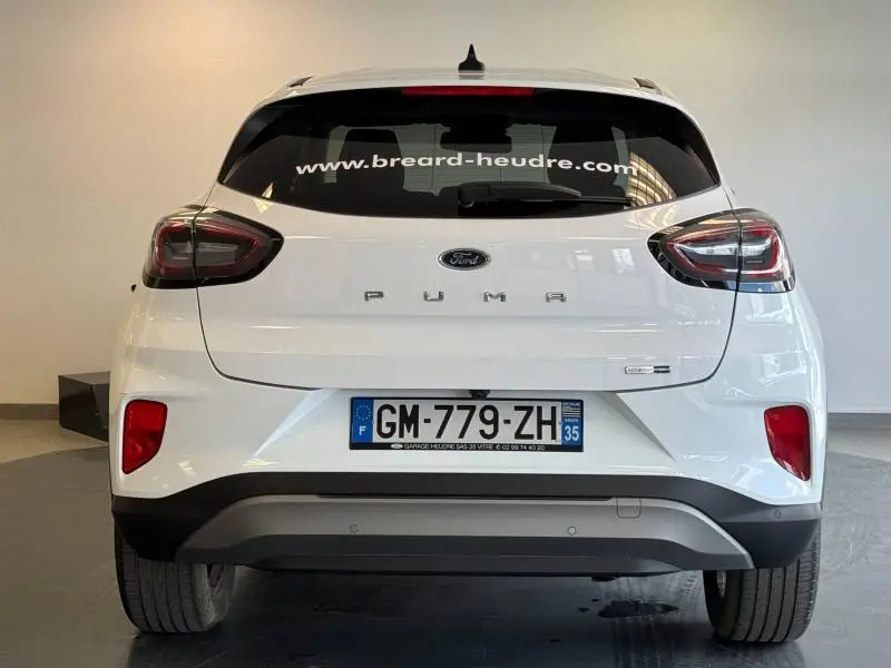 Vue arrière d'une Ford Puma blanc glacier avec feux LED et lunette arrière surteintée en intérieur showroom.