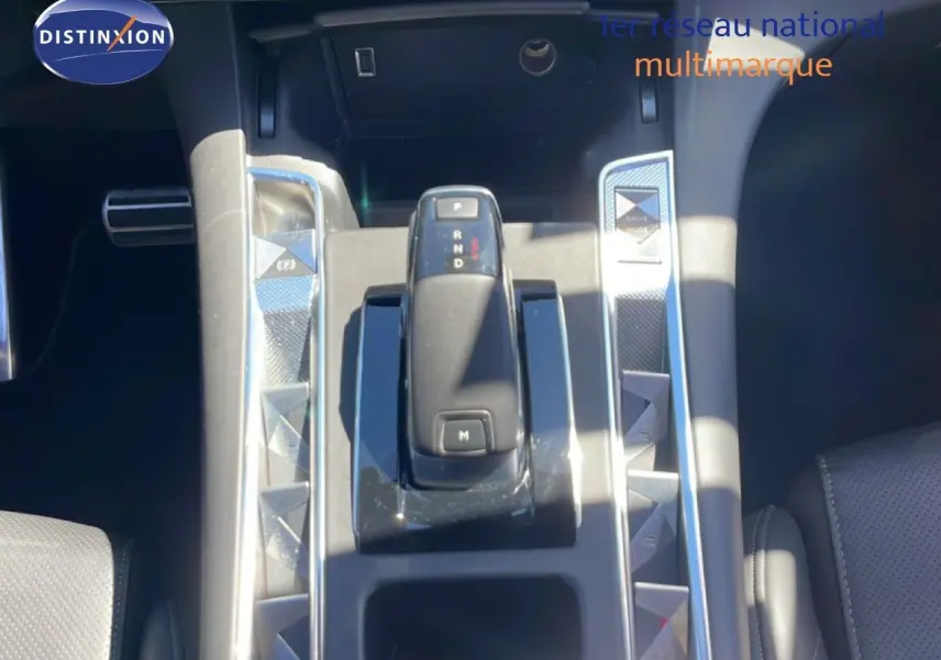 Vue rapprochée de la console centrale du DS7 2024 noir métal, avec levier de vitesse automatique et boutons triangulaires chromés.