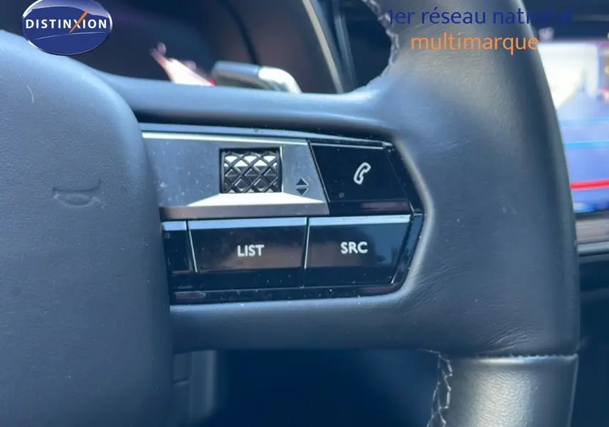 Gros plan sur les commandes gauche du volant en cuir noir du DS7 2024 noir métal, avec boutons LIST et SRC visibles.