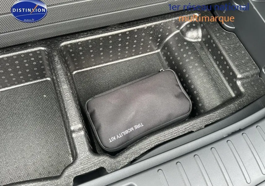 Rangement de coffre avec kit de mobilité noir dans un Hyundai Tucson blanc sérénité, vue intérieure arrière.