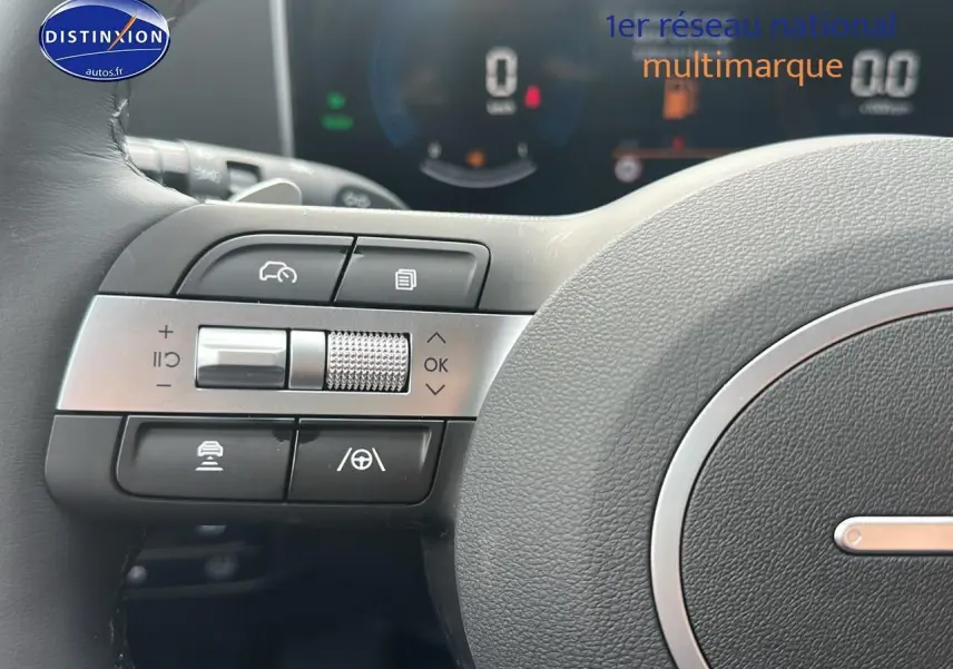 Gros plan sur les commandes à gauche du volant cuir du Hyundai Tucson blanc Sérénité 2025 hybride.