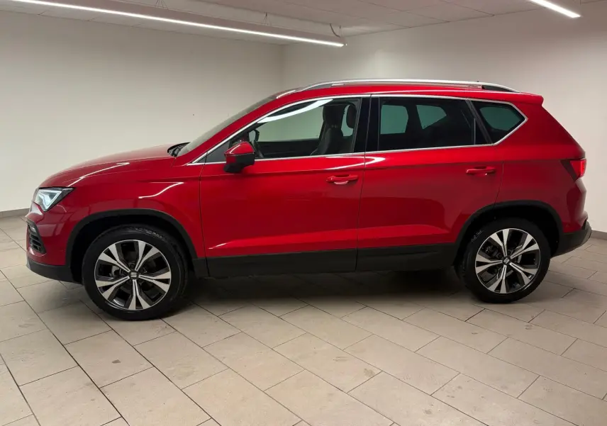 Vue de profil côté gauche d'un SEAT Ateca 2024 Rouge Velvet avec jantes alliage et toit ouvrant panoramique.