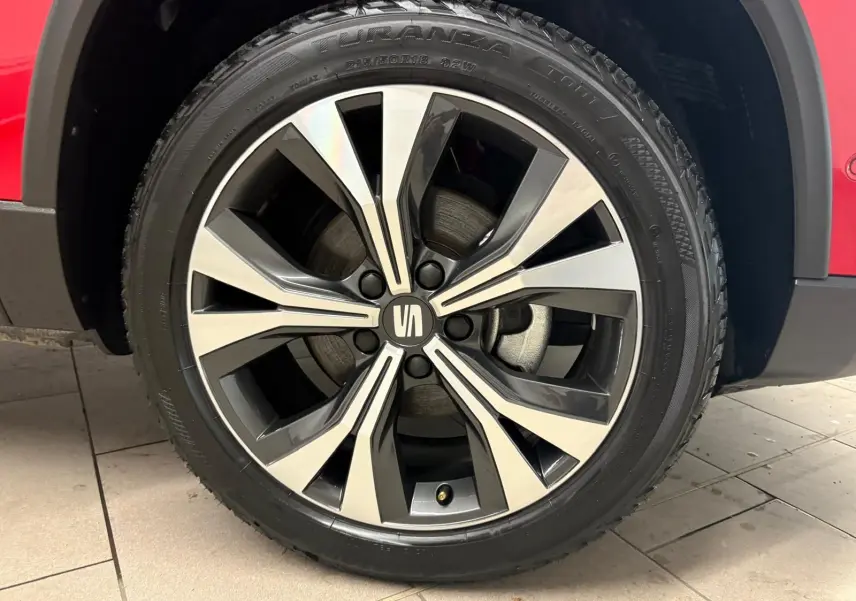 Gros plan sur la roue avant droite du SEAT Ateca 2024 Rouge Velvet, mettant en valeur la jante alliage bicolore.