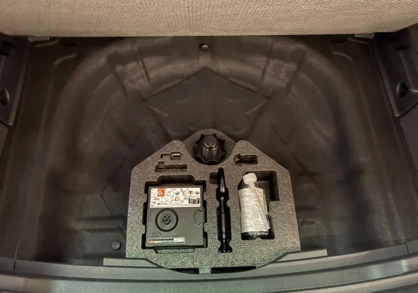 Vue plongeante sur le plancher de coffre à double fond du SEAT Ateca 2024, avec kit de réparation visible.