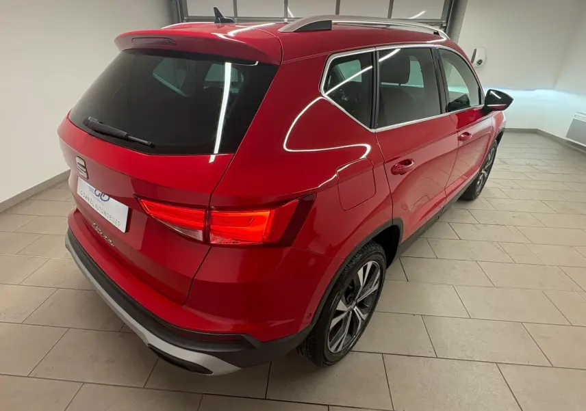 Vue 3/4 arrière droite du SEAT Ateca 2024 en Rouge Velvet métallisé, soulignant ses feux arrière allumés et ses jantes alliage.