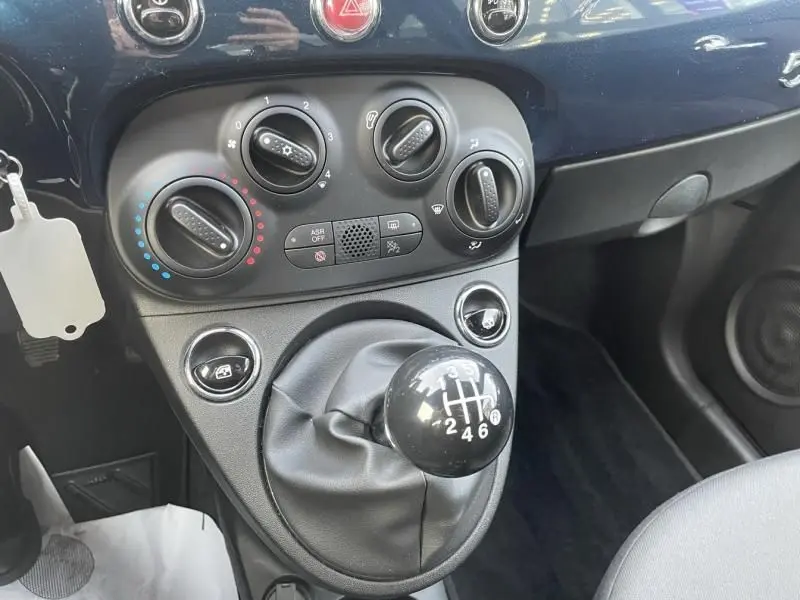 Gros plan sur la console centrale bleu métal de la Fiat 500 2023 avec levier de vitesse manuel et commandes de climatisation.