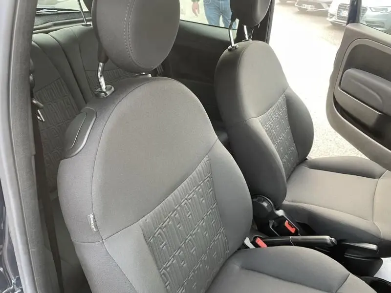 Vue intérieure des sièges avant gris foncé avec motif FIAT embossé, porte ouverte côté droit d'une FIAT 500 bleu métal 2023.