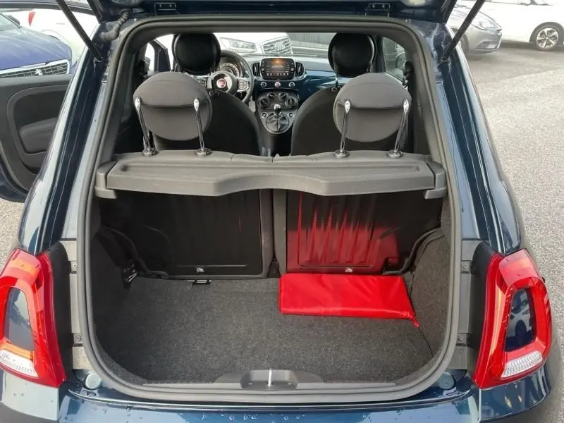 Coffre ouvert d'une Fiat 500 bleu métal 2023, vue arrière montrant l'intérieur et le tableau de bord.