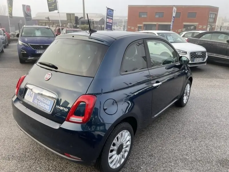 Vue 3/4 arrière droite d'une FIAT 500 bleu métal 2023 avec feux arrière distinctifs et jantes multibranches.