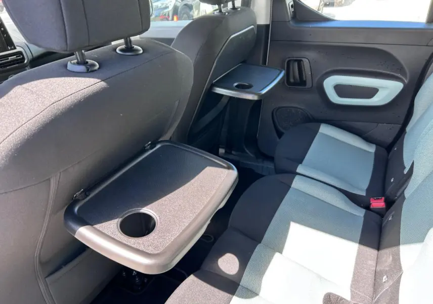 Vue intérieure côté droit des sièges arrière gris et noir d'un Citroën Berlingo avec tablettes rabattables fixées aux dossiers.