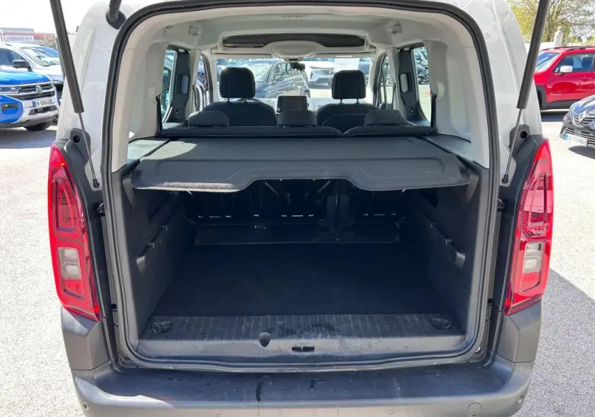 Vue arrière ouverte du coffre d'un Citroën Berlingo blanc 2020, montrant l'espace de chargement et les sièges arrière.