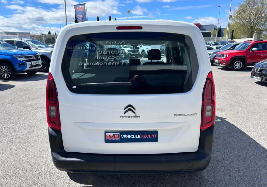 Vue arrière d'un Citroën Berlingo blanc 2020 avec hayon vitré et feux arrière verticaux, stationné en extérieur.