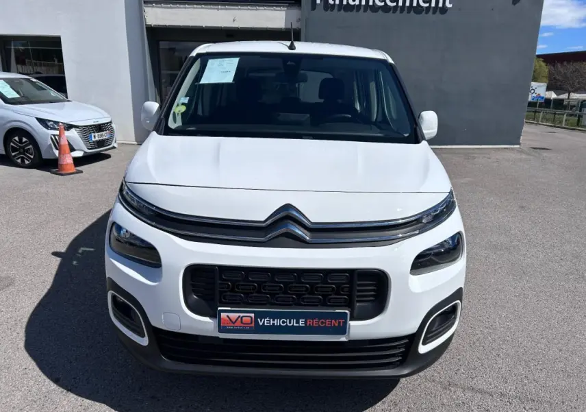 Vue avant d'un Citroën Berlingo blanc avec calandre noire et barres de toit visibles en extérieur.