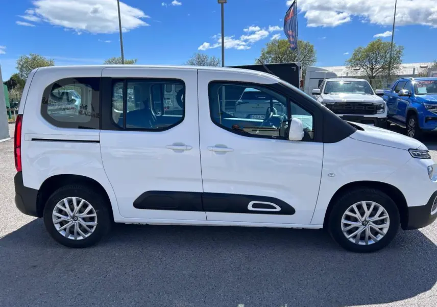 Profil côté droit du Citroën Berlingo blanc 2020 avec barres de toit et protections latérales noires.