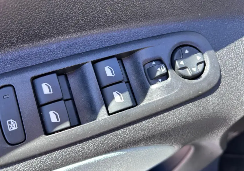 Gros plan sur les commandes des vitres et rétroviseurs électriques côté conducteur du Citroën Berlingo blanc 2020.