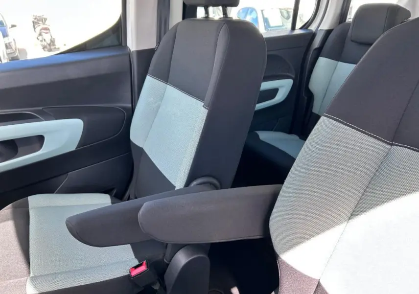 Vue intérieure côté droit montrant les sièges avant bi-ton gris et noir avec accoudoir du Citroën Berlingo blanc.