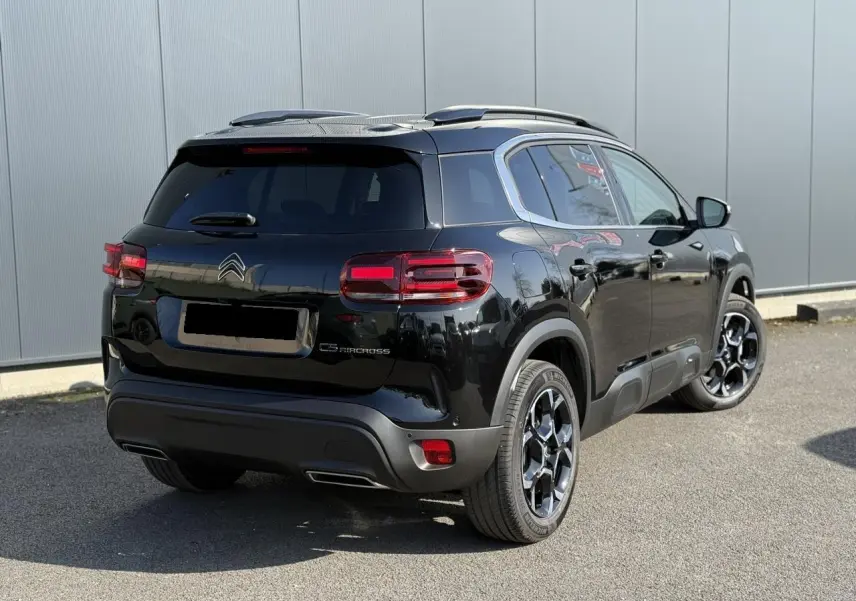 Vue 3/4 arrière droite du Citroën C5 Aircross noir Perla avec jantes alliage 18'' bi-ton et barres de toit noires.