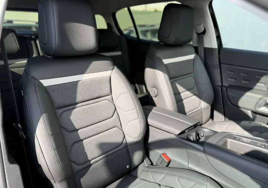 Vue intérieure de face des sièges avant gris foncé avec tissu et cuir, accoudoir central et console d'une Citroën C5 Aircross 2025.