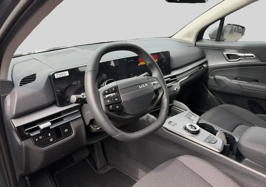 Intérieur avant du Kia Sportage 1.6 hybride 2026 vu côté conducteur, avec volant cuir multifonction et tableau de bord numérique.
