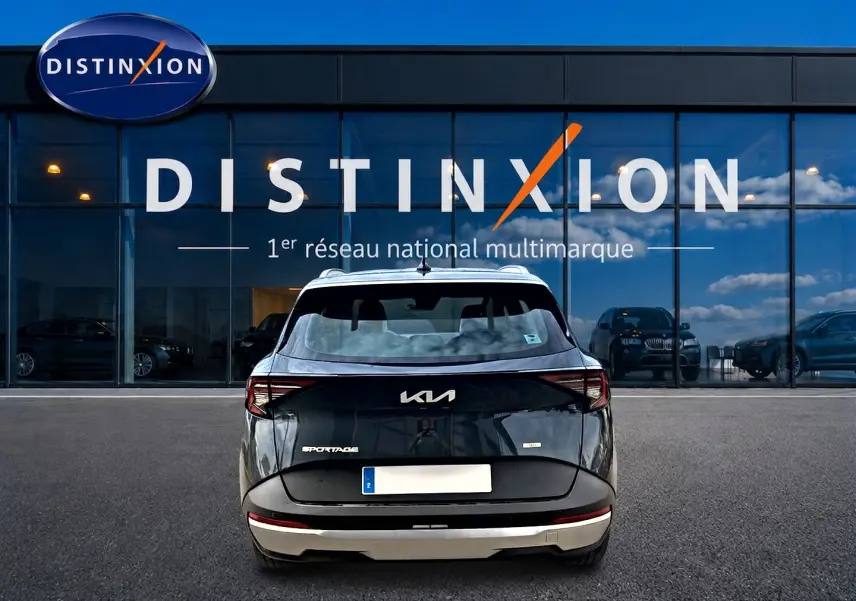 Vue arrière d'un KIA SPORTAGE 1.6 hybride gris eclipse, avec feux arrière LED et barres de toit visibles.