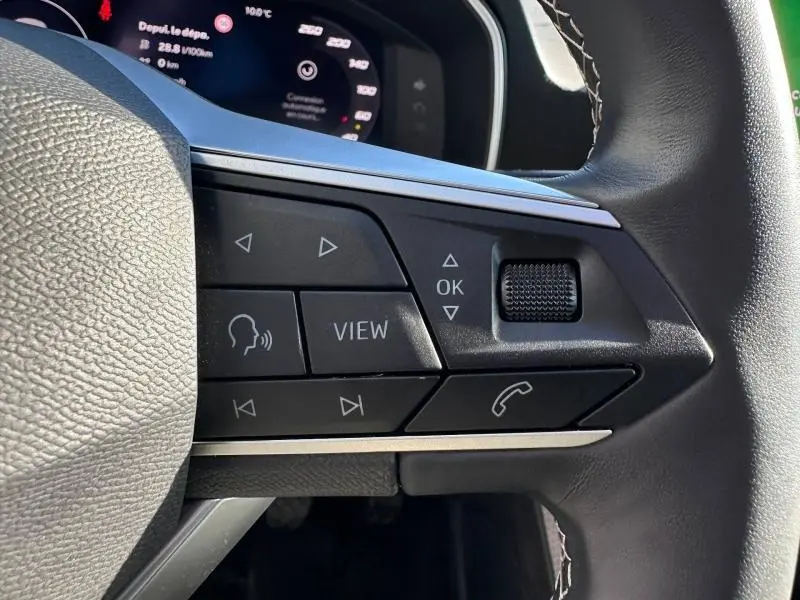 Gros plan sur les commandes multifonctions à droite du volant du SEAT LEON ST 2025, avec écran numérique en arrière-plan.