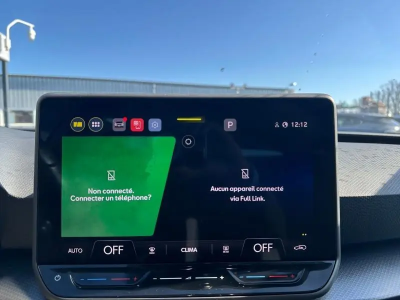 Vue intérieure centrée sur l'écran tactile du tableau de bord du SEAT LEON ST 2025, affichage multimédia et climatisation.