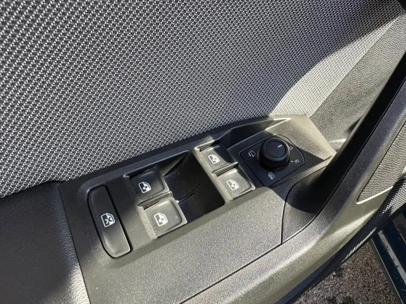 Gros plan sur les commandes des vitres et des rétroviseurs côté conducteur d’une SEAT LEON ST 2.0 TDI 115ch STYLE XL 2025.