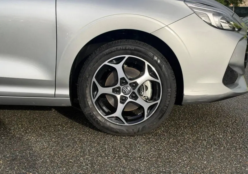 Gros plan sur la roue avant gauche et la partie avant d'une MG3 Cosmic Silver métallisé, avec jante alu distinctive.