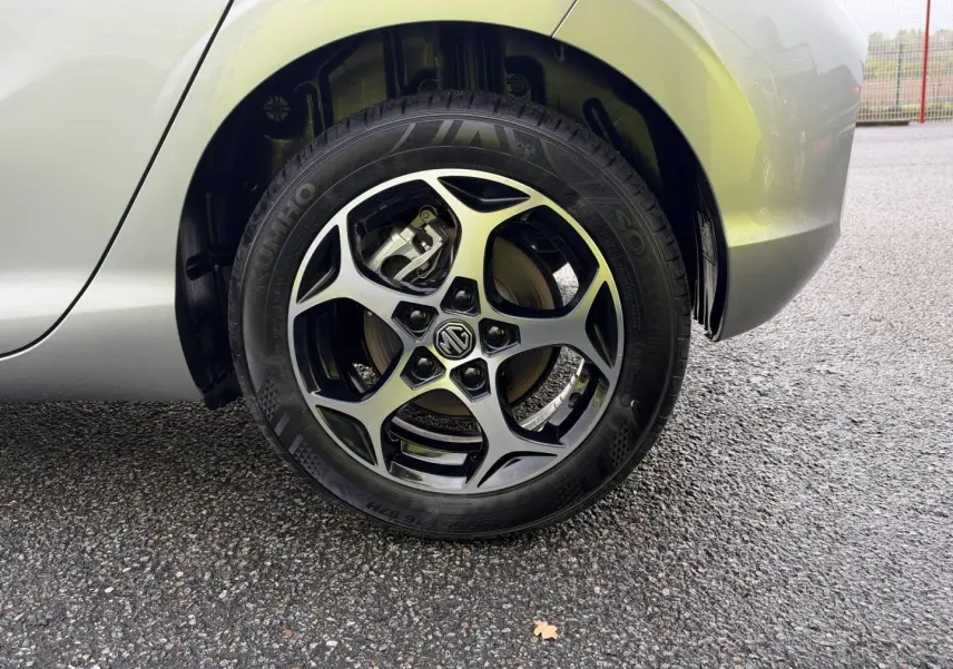 Gros plan sur la roue arrière droite d'une MG3 Cosmic Silver métallisé avec jante alliage noire et logo MG au centre.