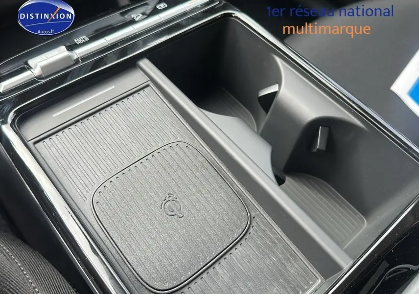 Gros plan sur la console centrale noire du Hyundai Tucson 2025 avec chargeur sans fil et porte-gobelets.