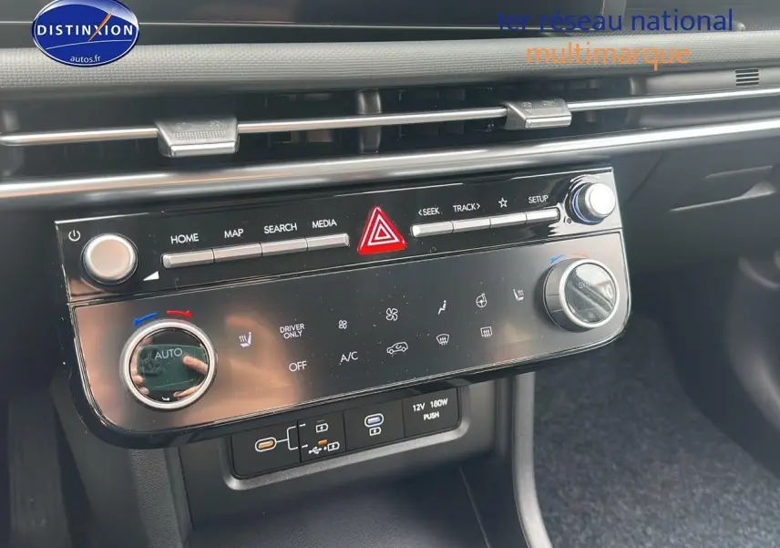 Vue rapprochée de la console centrale du Hyundai Tucson 2025 avec commandes climatisation et connectiques USB visibles.