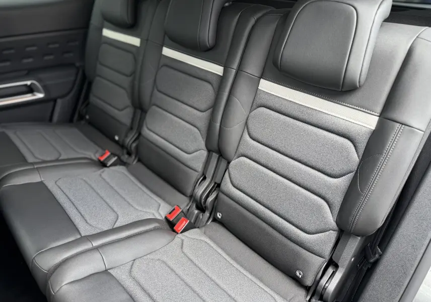 Vue rapprochée des sièges arrière en cuir noir et tissu gris du Citroën C5 Aircross 2025, avec ceinture rouge visible.