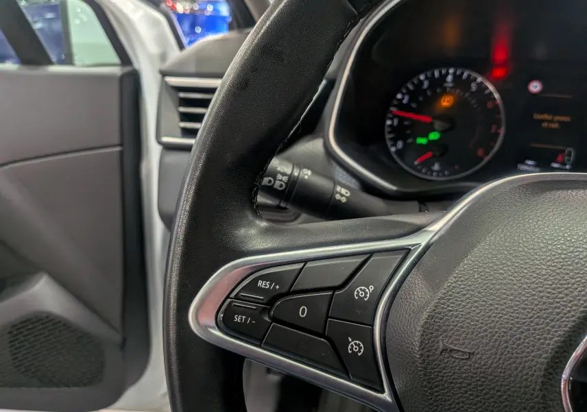 Gros plan sur le volant noir de la Renault Clio V TCe 100 Business, avec commandes de régulateur de vitesse visibles.