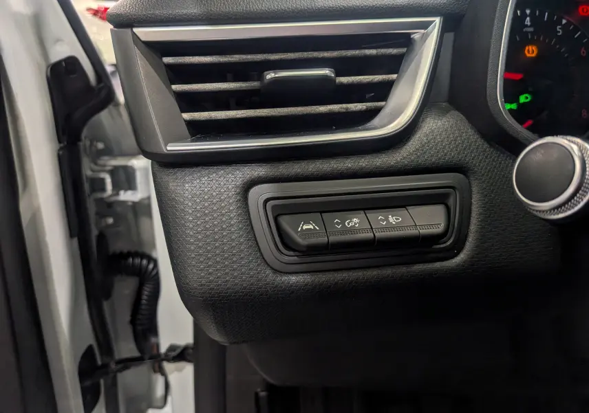 Détail des commandes d'aide à la conduite sur le tableau de bord noir d'une Renault Clio V blanc glacier, côté gauche.
