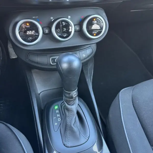 Vue rapprochée de la console centrale du Fiat 500X gris MY23, montrant la boîte auto et les commandes de climatisation manuelle.