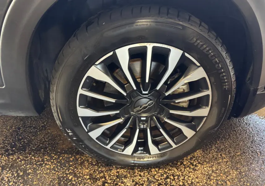 Gros plan sur la jante 16 pouces bicolore du côté avant droit d'un FIAT 500X gris MY23.